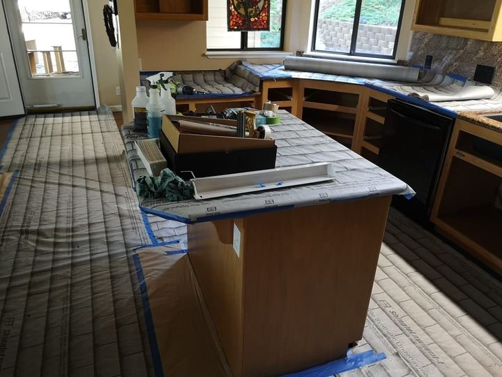 A kitchen fully masked and protected before cabinet work: counters, floors, and openings covered