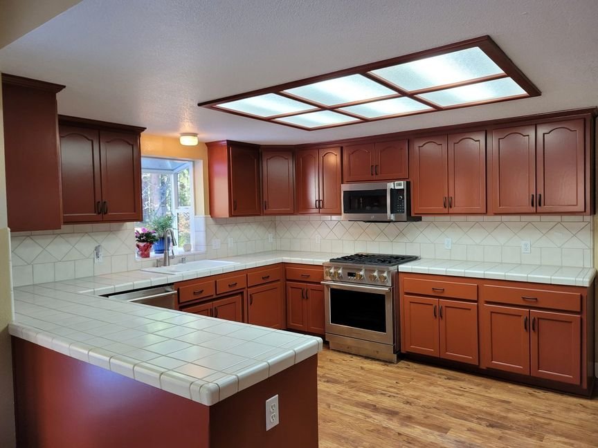A refinished kitchen with cabinets sprayed a warm terracotta and hardware reinstalled