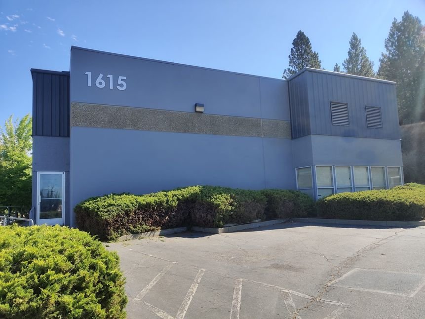 A repainted two-story business-park office building with a fresh gray and white exterior