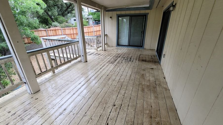 A deck with a worn solid-color finish peeling and flaking off the boards, the condition before any prep