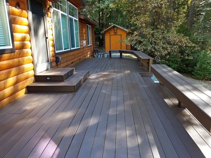 A finished cabin deck with a rich solid stain and built-in benches, boards even edge to edge