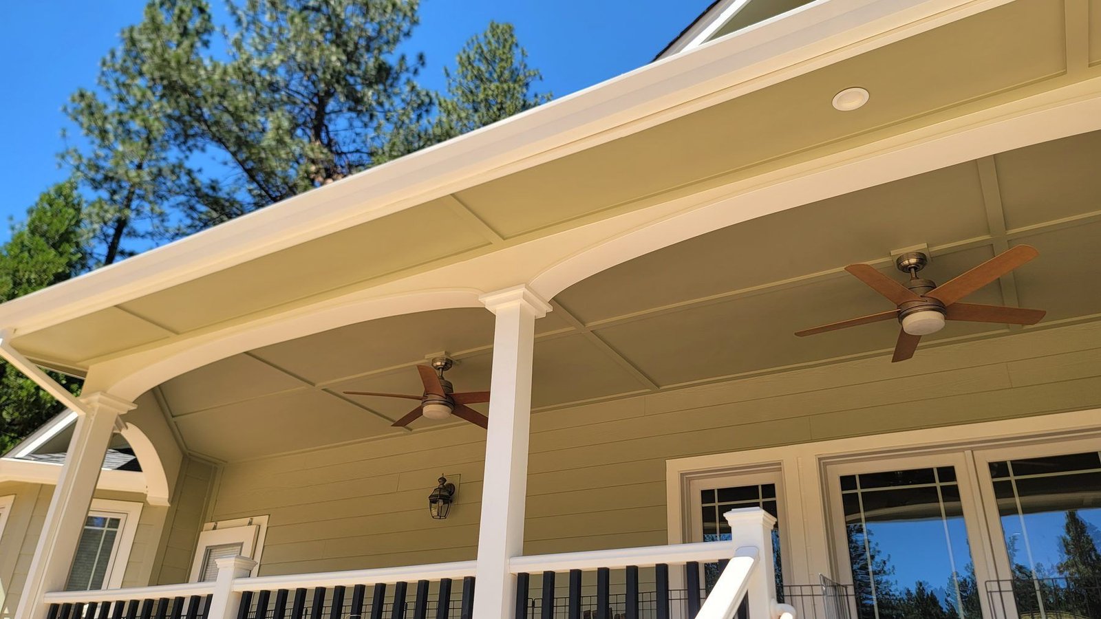 Looking up at a freshly painted porch ceiling, fascia and soffit with crisp trim lines and mounted fans
