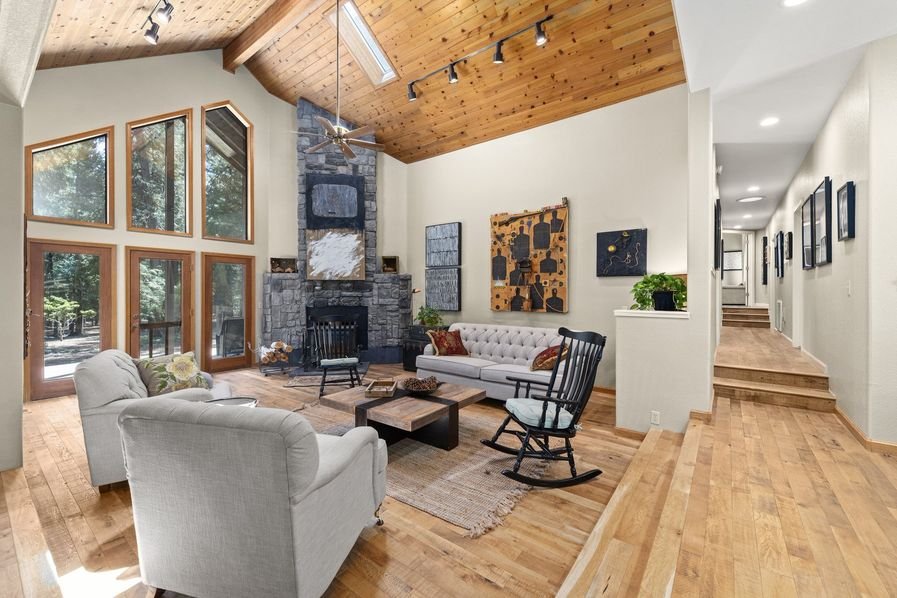 A finished great room with a vaulted wood ceiling, stone fireplace, and freshly painted walls