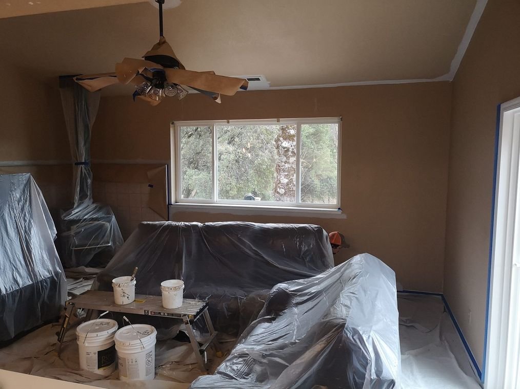 A living room masked before painting, the furniture and floors covered in protective sheeting