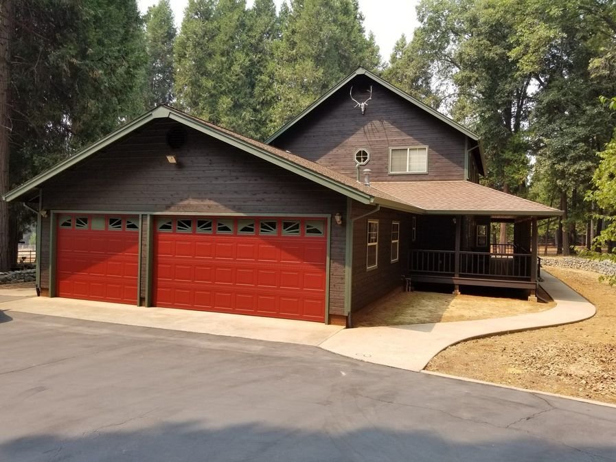 A dark-brown stained log home with a matching two-car garage and driveway